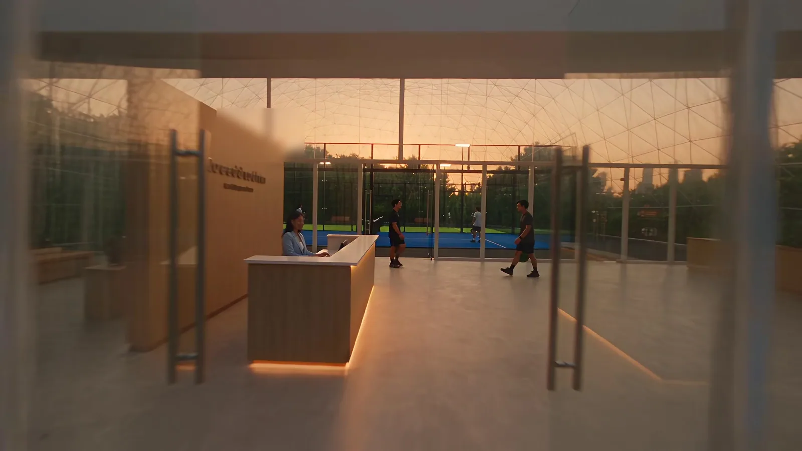 The Padelion front desk under the glass dome at dusk